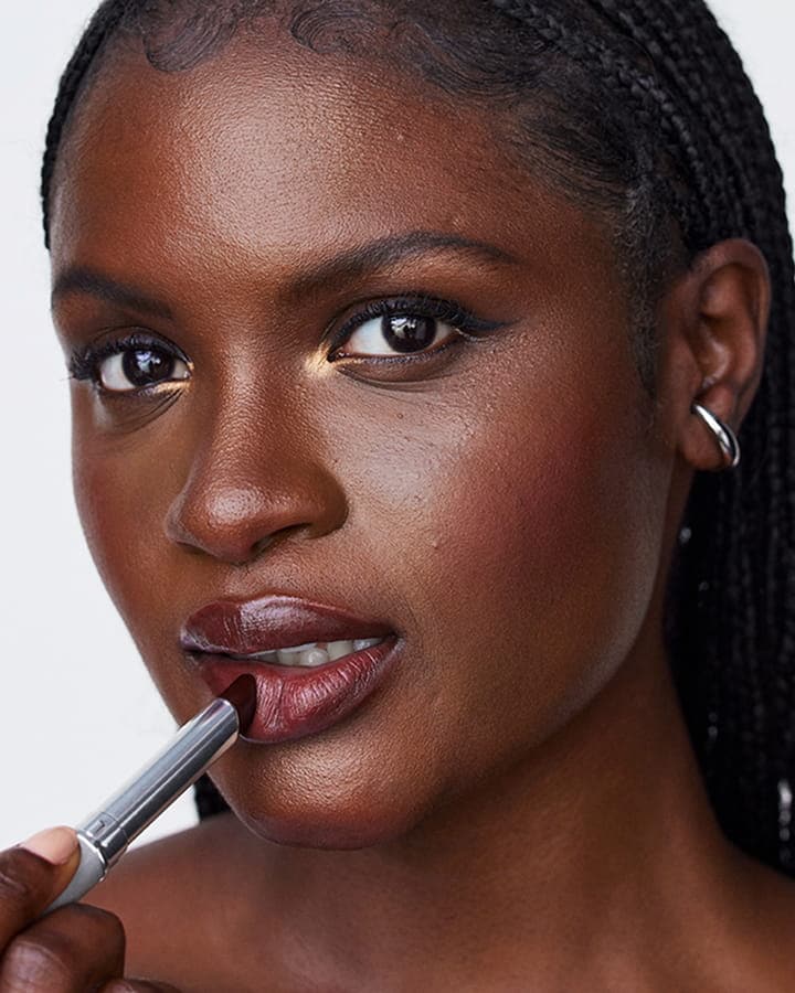 A close up shot of a model putting on a black honey lipstick 