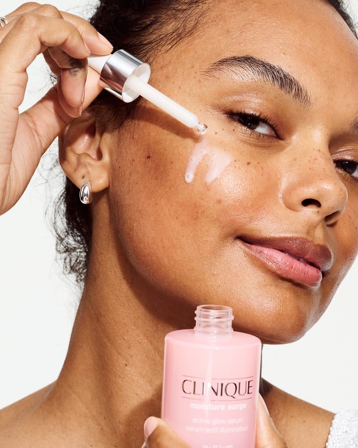 Close up of model applying Moisture Surge Serum to skin, focusing on product texture